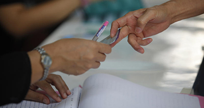 A voter hands an ID to an election official for checking at a polling unit in Bung Kum district in Bangkok on Sunday.