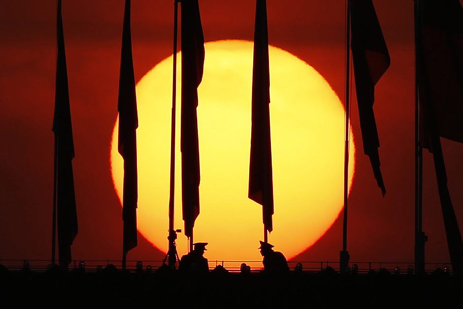 Two paramilitary policemen are silhouetted against the rising sun as they guard under flags on the roof top of the National Museum before the opening session of the third plenum of the 12th National People's Congress (NPC) in Beijing, China. — EPA