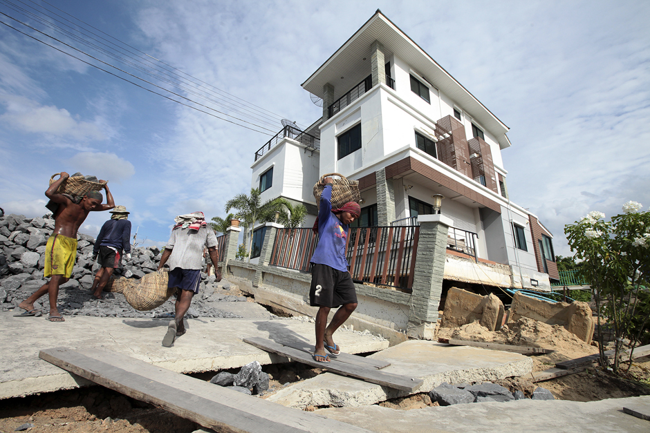 A worker carries a basket of rocks to fill cracks caused by land subsidence as a result of erosion along the Chao Phraya River bank in Ayutthaya. Photo by Patipat Janthong