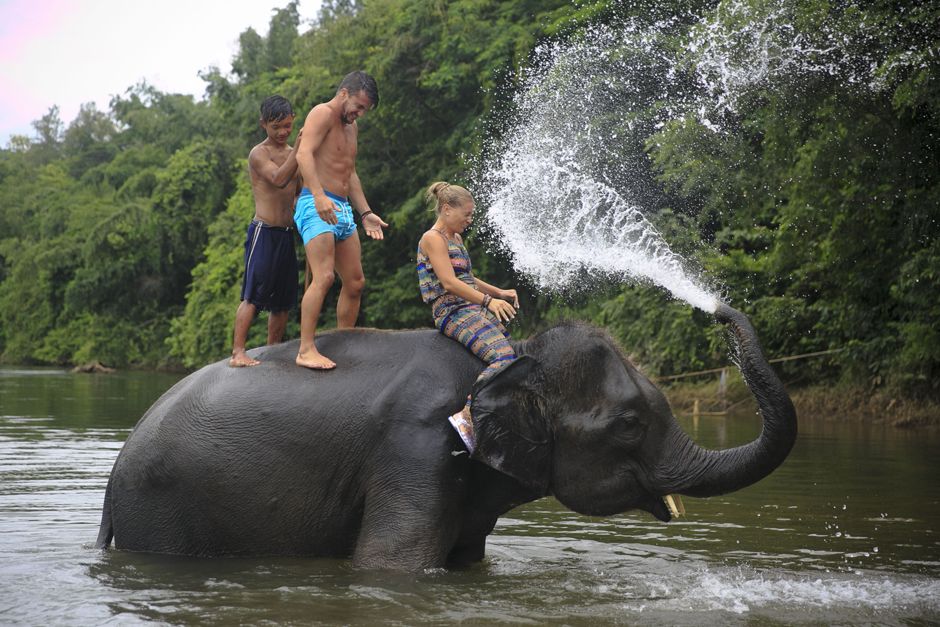 An elephant sprays water at tourists at the Kwai Noi river in Kanchanaburi province. - Seksan Rojjanametakun