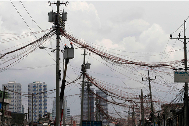 Workers standing in a hydraulic lift examine illegal electrical connections during a routine check on utility poles along a road in a slum area in Manila. The Philippines said Wednesday it would end Chinese technical involvement in running the country's power grid. (Reuters photo) Workers standing in a hydraulic lift examine illegal electrical connections during a routine check on utility poles along a road in a slum area in Manila. The Philippines said Wednesday it would end Chinese technical involvement in running the country's power grid. (Reuters photo)