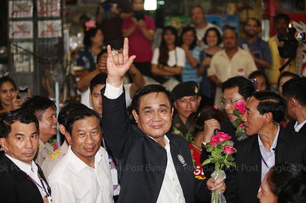 Prime Minister Prayut Chan-o-cha flashes an I-love-you sign while visiting the Chatchai market in Hua Hin on Friday. (Photo by Thiti Wannamontha)