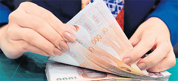 A Bangkok Bank teller counts baht notes at a branch in the capital. The Thai currency on Tuesday sank to 33.74/33.79 to the US dollar, its lowest level since September 2009.