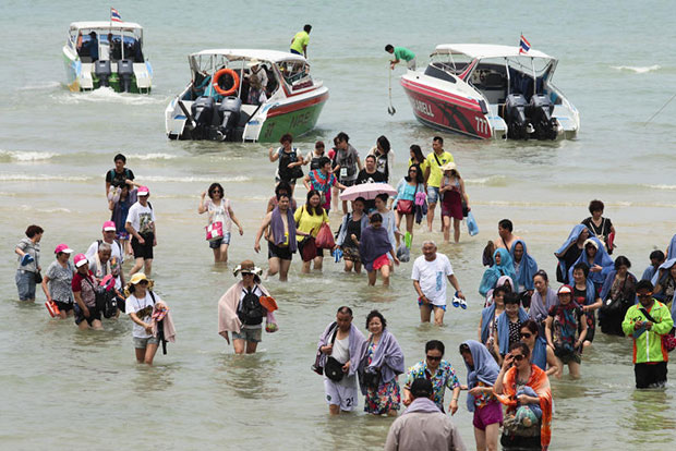 Chinese tourists return to the beach from ferry boats in Pattaya after visiting nearby Koh Lan in Chon Buri. (Bangkok Post file photo)