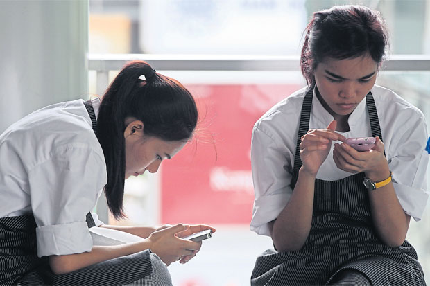 Workers take a break to check their mobile phones. The NBTC has decided not to extend the registration period for prepaid SIM cards, citing security reasons. SEKSAN ROJJANAMETAKUN