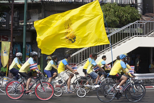 Cyclists with a flag of His Majesty the King flag ride past Wong Wian Yai, the site of the King Taksin the Great Monument, in Bangkok on Friday. (Photo by Pawat Laopaisarntaksin)