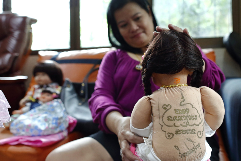 A magical incantation tattoo made by Buddhist monks is seen on the back of a Child Angel doll as the owner dresses it up at her house.