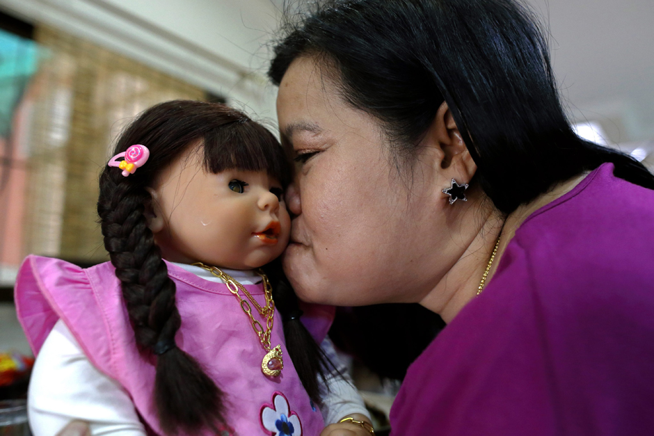 Thai devotee Ratchada Mahanavanont, 45, kisses her Child Angel doll at her house in Bangkok.