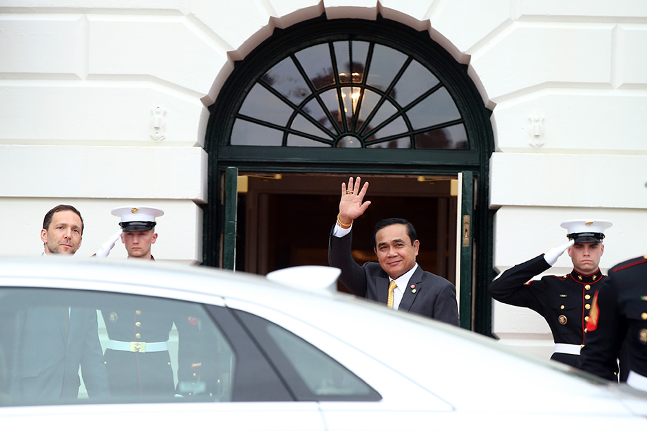 Prime Minister Prayut Chan-o-cha waves, as he is greeted by ambassador Peter Selfridge (left), chief of protocol of the United States, upon his arrival at the White House in Washington on March 31. — AP