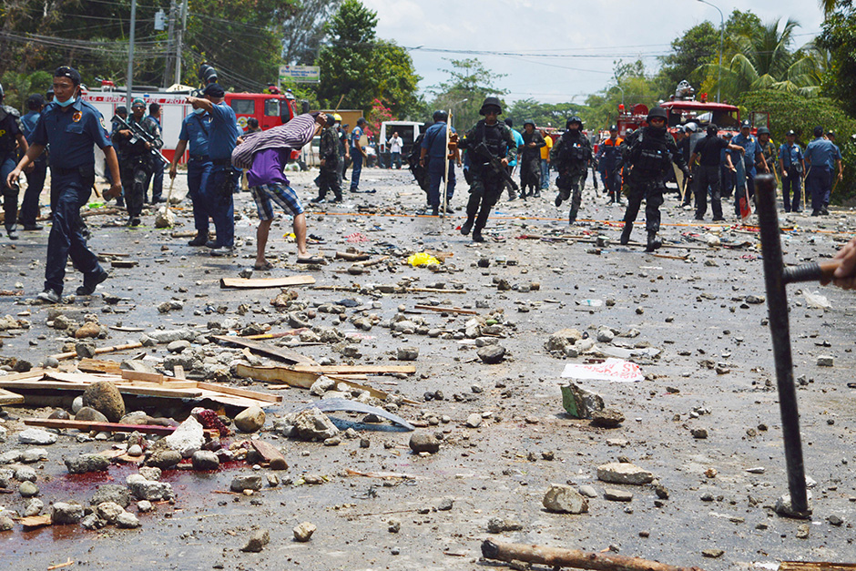 Philippine police clear a highway off of blood and debris following a violent protest in Kidapawan city. Officials say at least two people have been killed and dozens wounded when gunfire erupted as police attempted to clear a four-day-old protest by farmers, who have been demanding government financial aid in the wake of a seven-month drought in the province. — AP