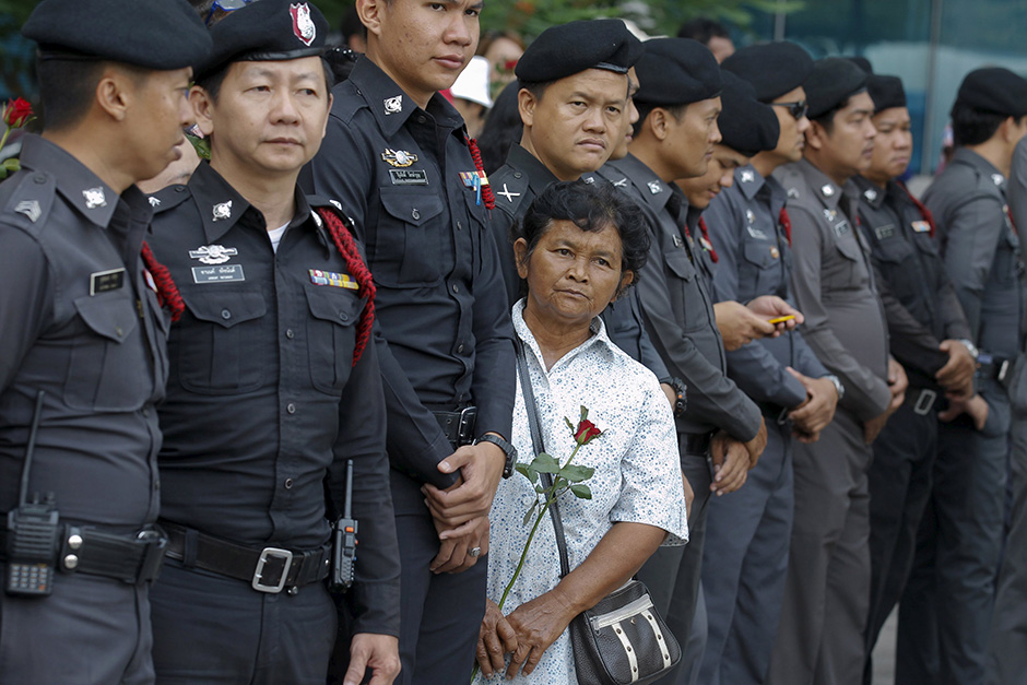 A supporter with a red rose stands among policemen, while waiting for ousted former prime minister Yingluck Shinawatra to arrive at the Supreme Court. — Reuters
