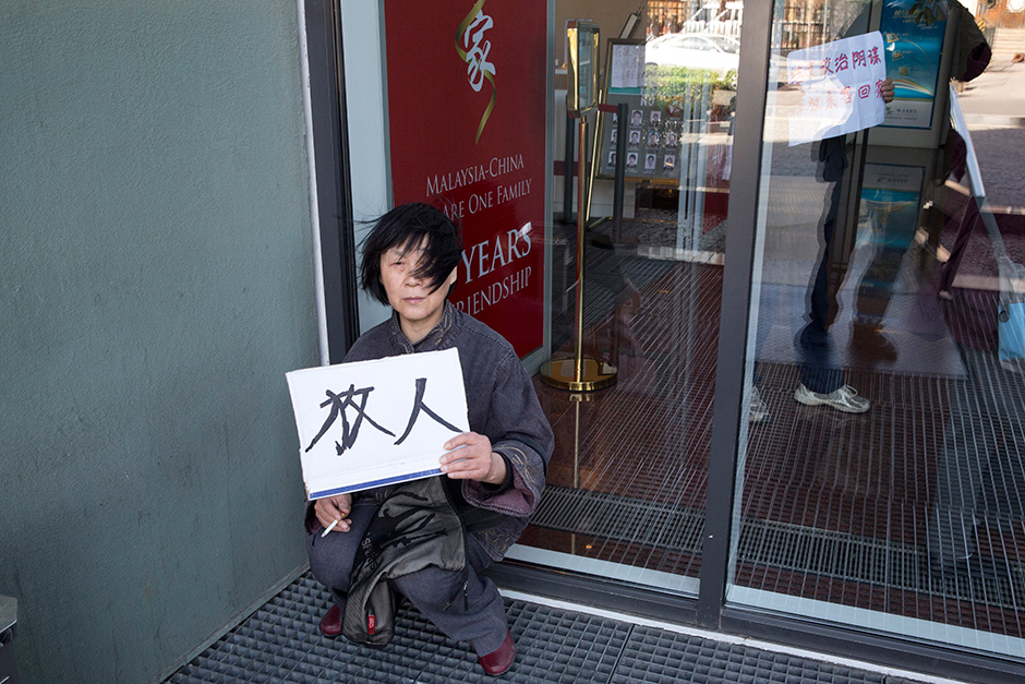 A relative of passengers on board the Malaysia Airlines flight MH370 that went missing March 8, 2014 protests with a card which reads