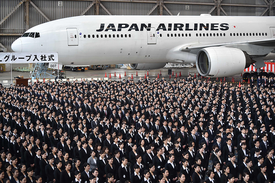 New employees of Japan Airlines Group attend an entrance ceremony at a hangar in Tokyo's Haneda airport. — AFP