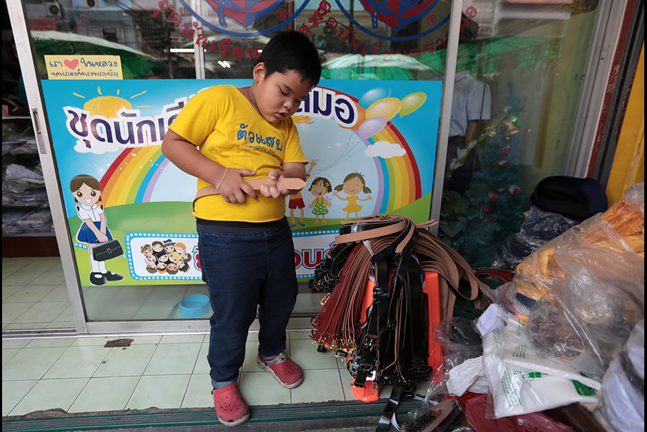 A boy tries a belt for size at a school uniform store in Bangkok's Bang Lamphu area on May 6, as many schools prepared to reopen for the new academic year. - Chanat Katanyu