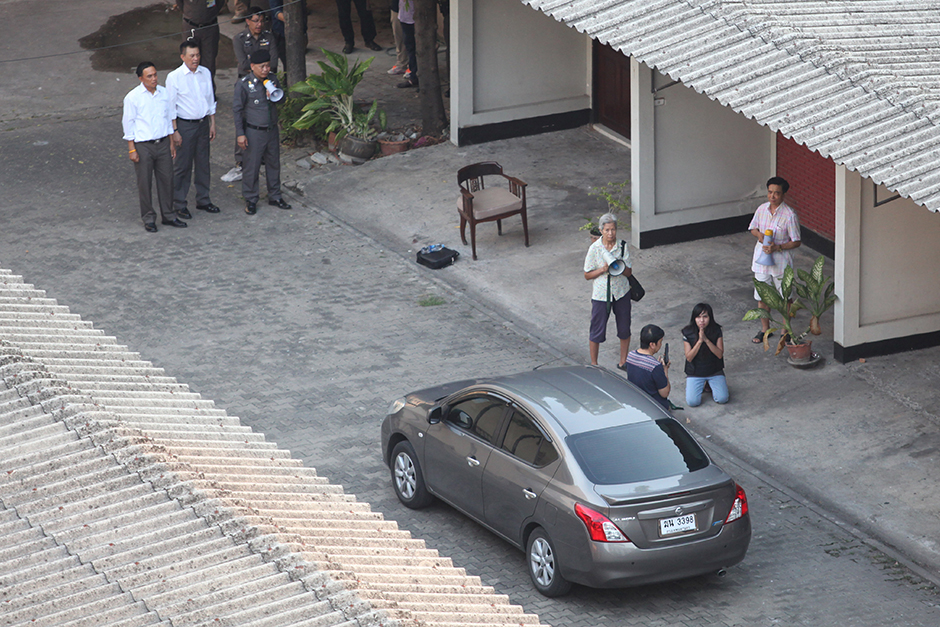 A female relative of Wanchai Danaitamonut, who fled after killing two fellow university lecturers, begs on her knees for him to surrender during negotiations on May 19. The doctorate lecturer shot himself in the head after a five-hour standoff with police and died. - Thiti Wannamontha