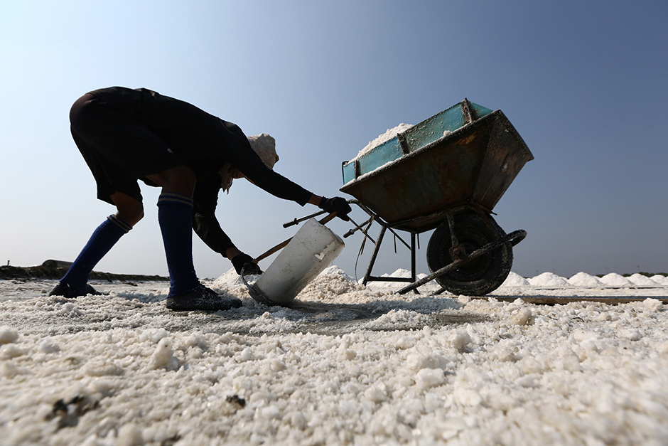 A farmer arranges salt into piles in Samut Songkhram on May 12. Stricter fishing rules have reduced the supply of fish to make fish sauce, which has also lowered the demand for salt. Drought has also led to a surplus of salt, causing prices to fall. - Seksan Rojjanametakun