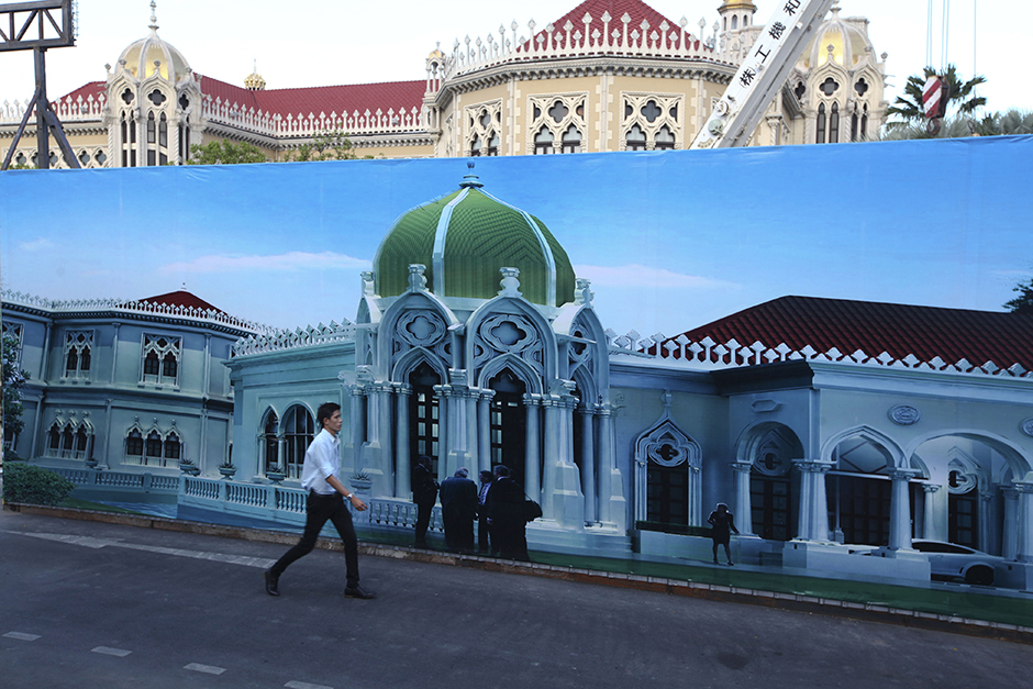 A man walks past a construction site inside the Government House compound on May 4. An elaborate reception building is being built behind the Thai Khu Fah building, Government house, on the orders of Prime Minister Prayut Chan-o-cha. - Seksan Rojjanametakun