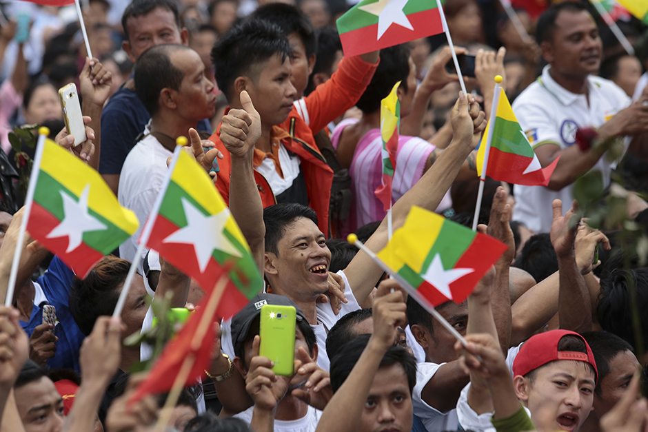 Thousands of Myanmar migrant workers wave national flags and cheer, as they await Suu Kyi's arrival at the fishing village in Samut Sakhon. - Patipat Janthong