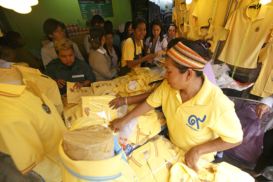 People look through yellow shirts on sale at Wang Lang Market near Siriraj Hospital in Bangkok. A team of doctors at Siriraj Hospital have treated the monarch's narrowed coronary arteries, and the outcome is satisfactory, according to the 27th statement issued by the Royal Household Bureau on Tuesday. - Seksan Rojjanametakun