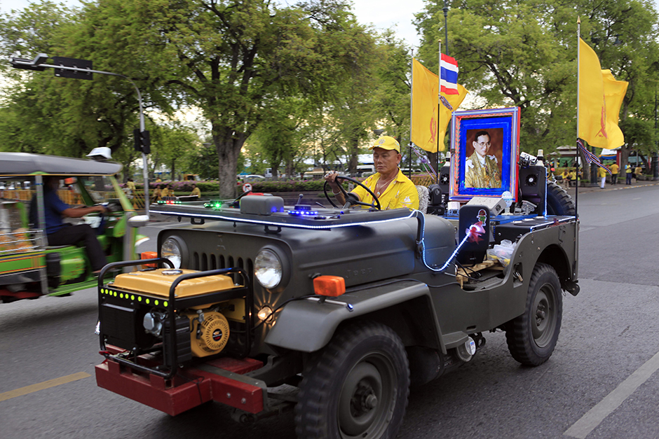 A man drives a jeep with a portrait of His Majesty the King in the back seat around Sanam Luang, Bangkok. - Apichart Jinakul