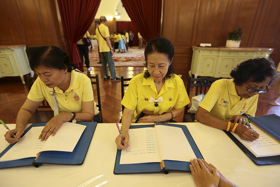 Thais sign well-wishing books in front of the King's portrait at the Sahathai Samakom Pavilion inside the Grand Palace. - Patipat Janthong