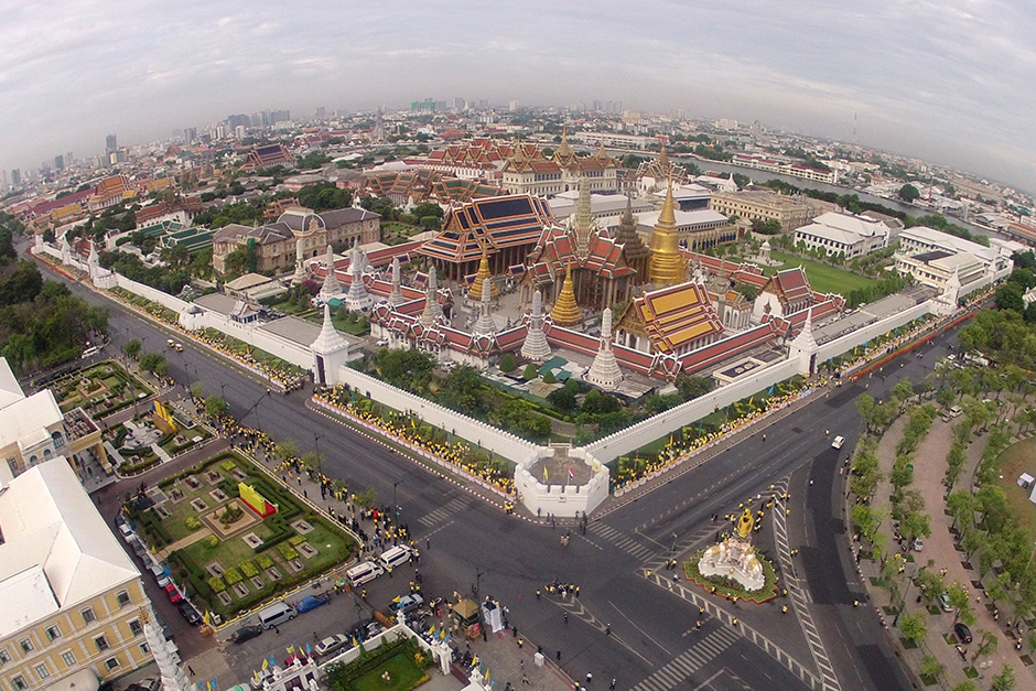People, many wearing yellow, give offerings to Buddhist monks outside the Grand Palace in Bangkok during the celebrations marking the 70th anniversary of His Majesty the King's accession to the throne. - Pattarapong Chatpattarasill