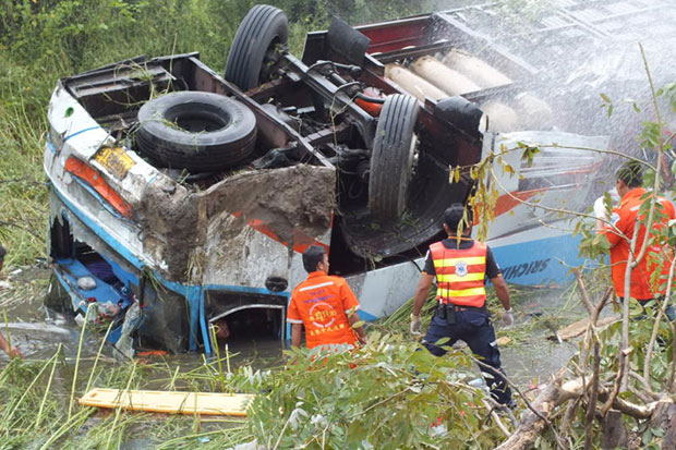 Rescue workers try to reach passengers trapped inside an overturned double-decker tour bus in Nakhon Ratchasima. Three people were killed in the accident and 20 injured. (Bangkok Post file photo)