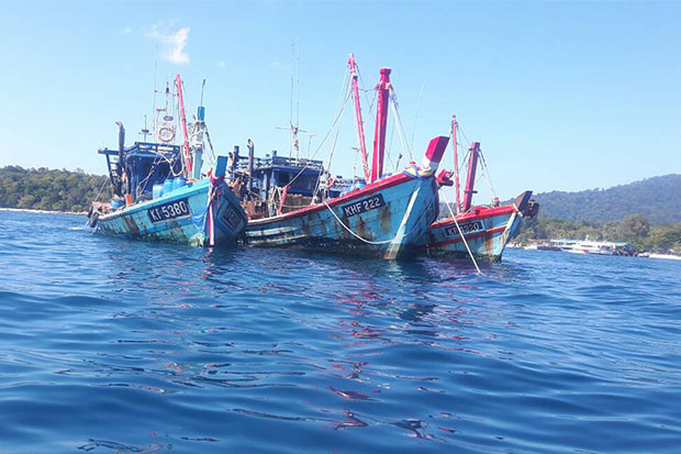 Three Malaysian-flagged fishing vessels spotted fishing illegally in Thai waters off Satun on Jan 7 are seized and 12 Thai men on board, including three skippers and nine crew members arrested. (Photo by Achadtaya Chuenniran)