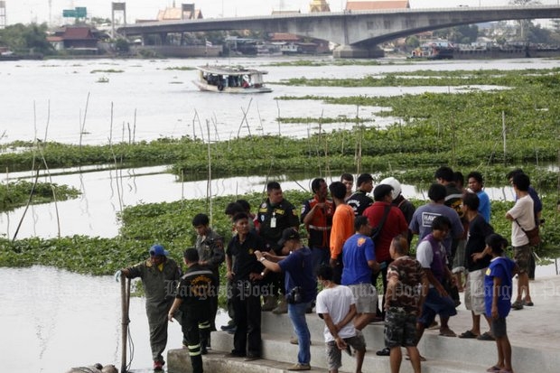 People watch as rescue workers retrieve a human torso from the Chao Phraya River Sunday near Wat Phothongbon in Nonthaburi's Pakkret district. (Photo by Thanarak Khunton)