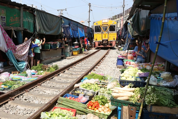 A train slowly makes its way through the folding umbrella market in Samut Songkram on Friday. (Photo by Pattarapong Chatpatarasill)