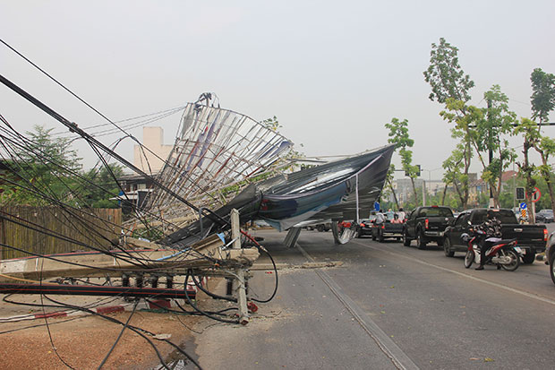 A summer storm uproots a power pole and causes a large billboard to collapse at Seechum intersection in Muang district of Lampang, blocking traffic in the area. (Photo by Aswin Wongnorkaew)