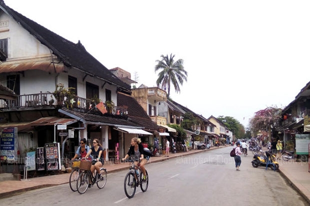 Tourists pedal through the old Lao capital of Luang Prabang. Thailand proposed stronger tourism links with Laos at talks between the Thai and Lao prime ministers on Wednesday. (Photo by Pongpet Mekloy)