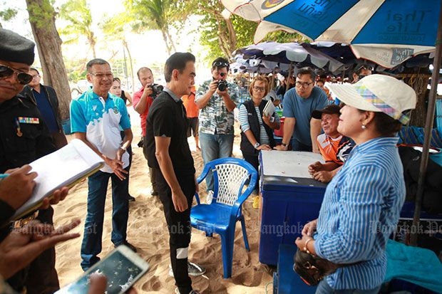 A deckchair and umbrella rental operator (right) whose staff were accused of chasing away tourists for setting up their own mats tries to explain her side of the story to officials at Jomtien beach on Saturday. (Photo by Chaiyot Pupattanapong)