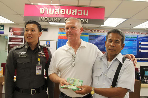 Wimol Treepat (right), a taxi driver, returns the money left in his taxi to his passenger David Collinson at the police unit of Suvarnabhumi airport (photo by Sutthiwit Chayutworakan)