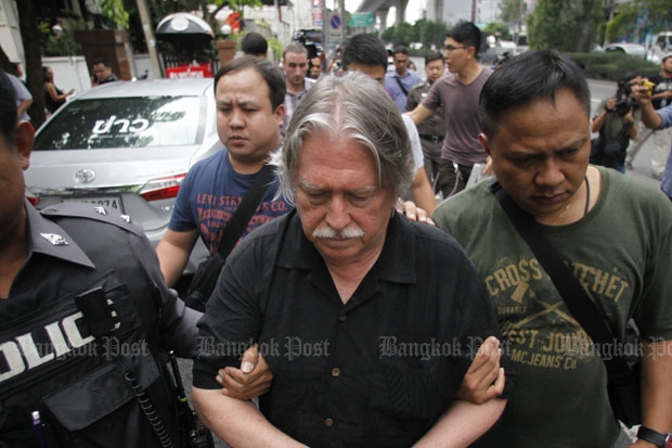 Police lead away James Douglas Eger, one of the three foreigners, arrested following the raid on an alleged passport-forgery operation in Phra Khanong district of Bangkok on Friday. (Photo by Pattarapong Chatpattarasill)