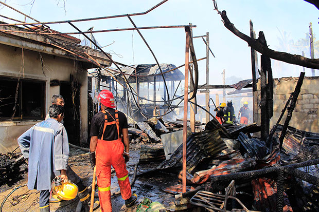 Firemen survey the ruins of five houses belonging to a single family that were destroyed by a blaze in Nakhon Sawan's Muang district on Thursday, leaving the owners devastated and homeless. (Photo by Chalit Pumruang)