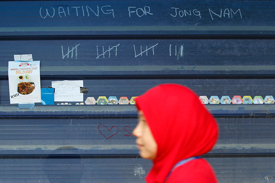 A woman walks past a wall marking the number of days the media cover the North Korean assassination outside a Kuala Lumpur Hospital. — AP