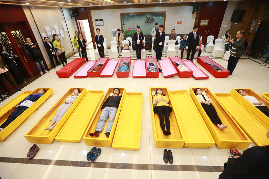 People lie in coffins during an opening day of a funeral parlour in