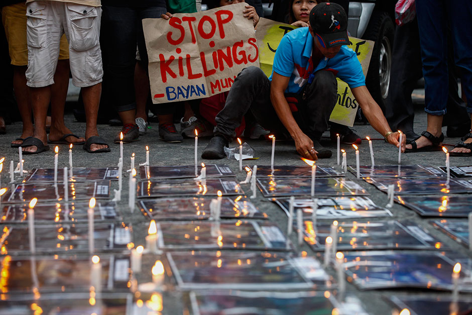 A human rights advocate places candles on the ground in a symbolic call for justice for victims of extra-judicial killings and justice for Filipino student Kian Loyd delos Santos who was allegedly killed in a police anti-illegal drugs operation on Aug 16, during a demonstration outside the Philippine National Police headquarters in Quezon City, east of Manila. — EPA