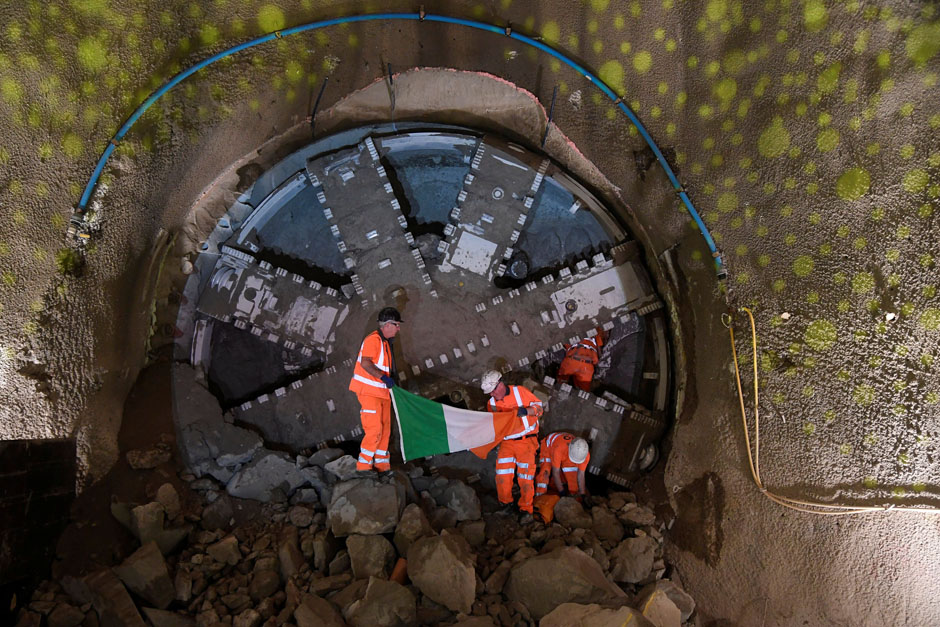Workers hold an Irish national flag as they emerge from behind a giant boring machine being used to tunnel during the Northern Line extension project in the Kennington and Battersea area of London, Britain. — Reuters