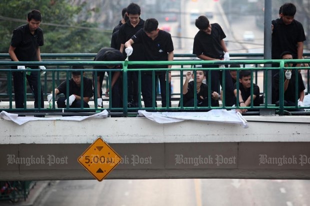 As the government was announcing the start of a 20-year education plan, it also was drafting vocational students to paint the railing on the skywalk around the Victory Monument on their day off Sunday. (Photo by Wichan Charoenkiatpakul)