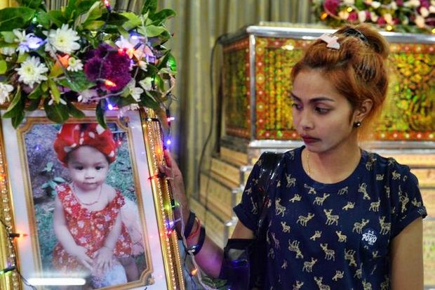 Jiranuch Trirat, mother of 11-month-old daughter Natalie, who was killed by her father with the murder broadcast on Facebook, stands next to a picture of the girl, nicknamed Beta, at a temple in Phuket on Tuesday. (Reuters photo)