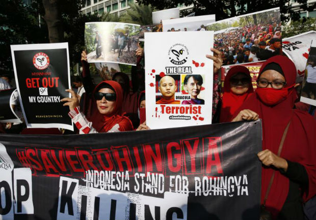 Indonesian Muslim activists hold a protest banner showing Myanmar State Counsellor Aung San Suu Kyi (right) and Myanmar nationalist Buddhist monk Wirathu (left) during a protest against Myanmar's alleged persecution of its Muslim Rohingya minority at a main roundabout in Jakarta, Indonesia, on Sunday. (EPA photo)