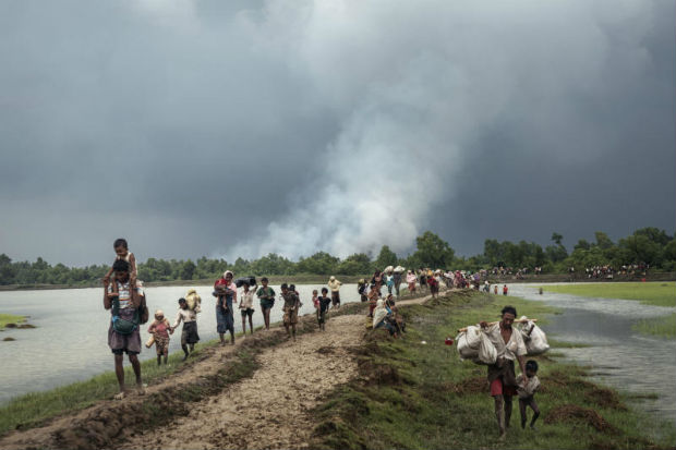 Villages burn in the distance as Rohingya refugees walk near the Naf River separating Myanmar and Bangladesh, near Palong Khali, Bangladesh, Sept 4, 2017. (Adam Dean/The New York Times)