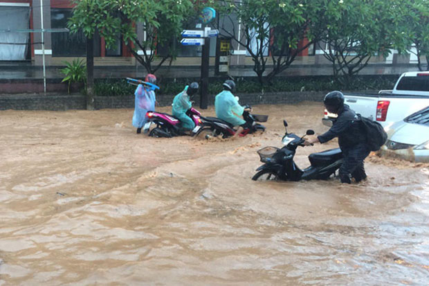 Motorcyclists wade through floodwaters in Patong area of Phuket on Friday after heavy rain. (Photo by Preecha Ritthirtree)