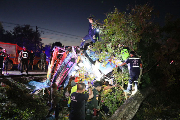 Rescue workers examine the wreckage of a Bangkok-Nan bus after it veered off the road and struck a tree in Bung Na Rang district of Phichit early on Saturday. One person was killed. (Photo by Sitthipoj Kebui)