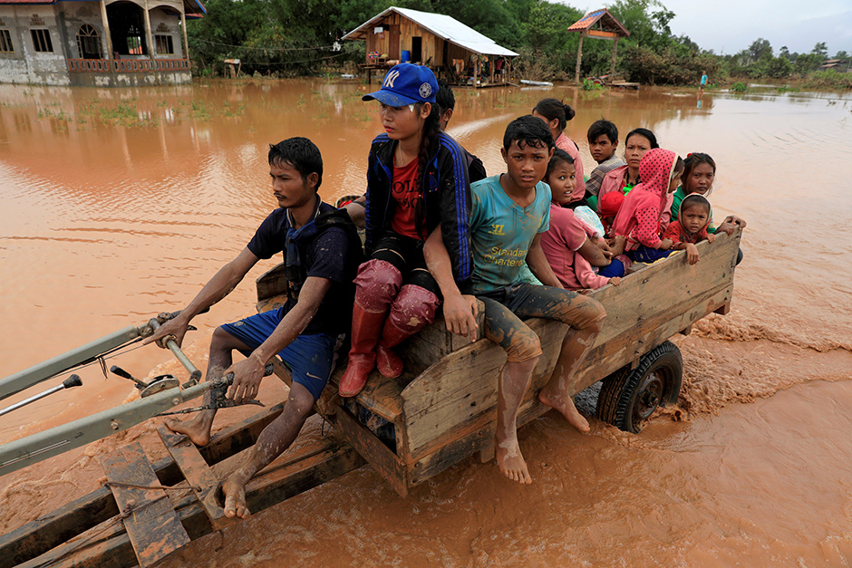 People sit on a locally made vehicle on Thursday as they travel during the flood. — Reuters