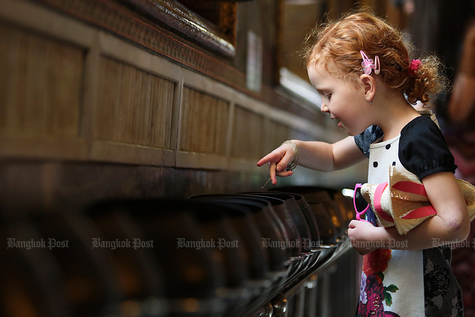Giving back: A little girl donates a coin to the temple's collection fund. Photo: Patipat Janthong