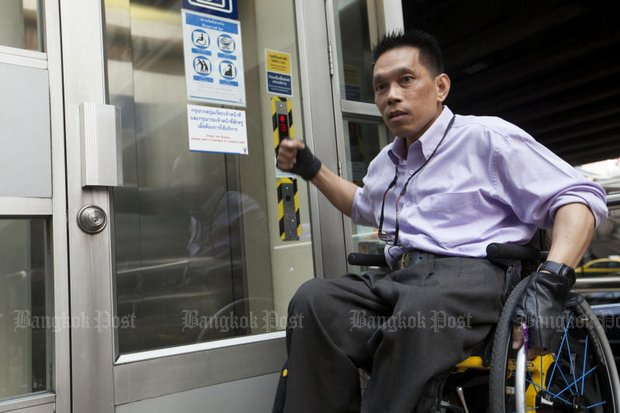 The wheelchair-bound, equal-access activist Manit 'Saba' Intharapim refused to sign a paper Monday attesting he is really entitled to use a BTS Skytrain elevator. Here, he reenacts the scene when he punched the glass elevator entrance door. (Photo by Pawat Laopaisarntaksin