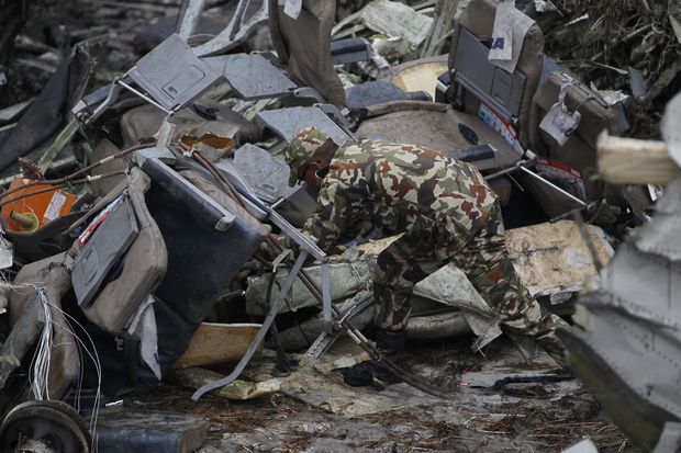 A Nepalese rescuer searches amid the debris after a passenger plane from Bangladesh crashed at the airport in Kathmandu on Monday. (AP photo) A Nepalese rescuer searches amid the debris after a passenger plane from Bangladesh crashed at the airport in Kathmandu on Monday. (AP photo)